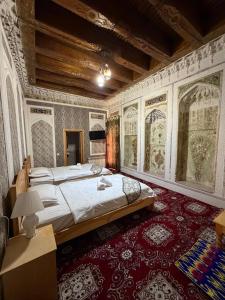a bedroom with a large bed and a red carpet at Boutique ALISHER in Bukhara