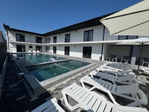 a group of white lounge chairs and a swimming pool at Hotel Elena Solotvino in Solotvyno