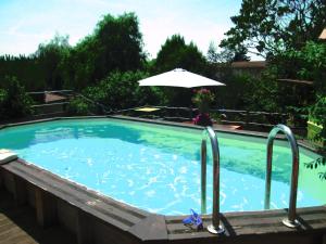 a large swimming pool with an umbrella in a yard at La Pause in Craponne