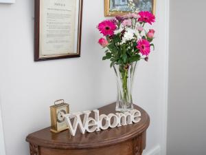 a vase of flowers on a table with a welcome sign at Rosaire Guest House in Llandudno