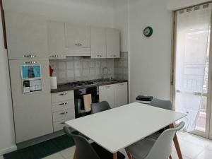 a white kitchen with a white table and chairs at Colibrì in Bordighera