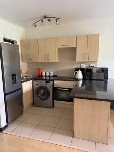 a kitchen with wooden cabinets and a washer and dryer at The Greenside Getaway in Roodepoort