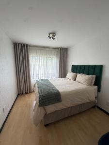 a bedroom with a large bed with a green headboard at The Greenside Getaway in Roodepoort