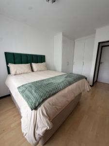 a bedroom with a large bed with a green headboard at The Greenside Getaway in Roodepoort
