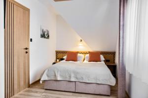 a bedroom with a bed with white sheets and orange pillows at Pokoje KAMILA - Apartament 5 min pieszo do Kotelnicy in Białka Tatrzańska +7 photos