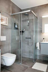 a bathroom with a shower with a toilet and a sink at Laya Living Lucerne - Kriens in Lucerne