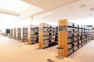 a library with several stacks of books on shelves at Tsukino HOTEL in Sakata