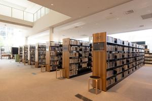 a library with several stacks of books and stools at Tsukino HOTEL in Sakata