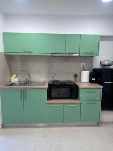 a kitchen with green cabinets and a sink at Olive tree studio ,Corfu Town in Ágios Rókkos