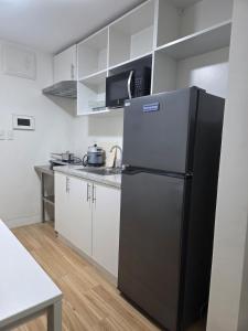 a kitchen with a black refrigerator and white cabinets at Cozy Studio Long Stays Welcome in Biñan