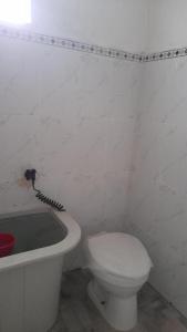 a white bathroom with a toilet and a bath tub at Bali Home Taksu in Jatiluwih