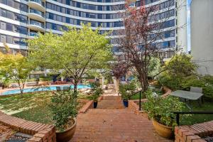 a garden with trees and a pool in a city at Lakefront Panorama – Sky Collection Suite in Canberra