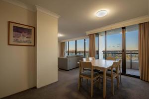 a dining room with a table and chairs and a couch at Lakefront Panorama – Sky Collection Suite in Canberra
