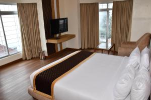 a hotel room with a large bed and a television at Hotel Oxina Cizel in Kodaikānāl