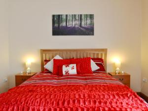 a bedroom with a red bed with red and white pillows at The Dairy - Op3 in Carmarthen
