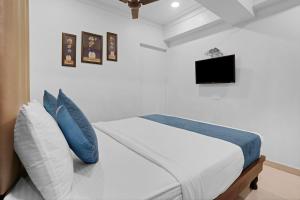 a bedroom with a bed with blue pillows and a tv at Hotel Dream Inn Thane in Thane