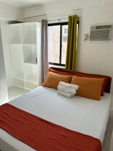ein Bett mit orangefarbenen und weißen Kissen und ein Fenster in der Unterkunft Leonardo Hostel in Anda