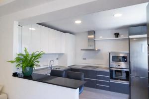 a kitchen with white cabinets and a stainless steel refrigerator at Central Torremolinos Luxury Apartment in Torremolinos