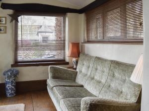 a living room with a couch and two windows at Stable Cottage in Windermere