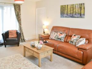 ein Wohnzimmer mit einer braunen Ledercouch und einem Couchtisch in der Unterkunft Thistle Dee in Wooler