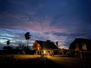 a small house with a thatched roof at sunset at Delft Jungle Beachfront Villa in Delft East