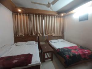 a bedroom with two beds and a window with curtains at Hotel Sikder-02 Residential in Dhaka +5 photos
