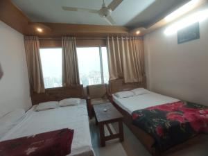 two beds in a room with a window at Hotel Sikder-02 Residential in Dhaka