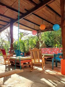 a patio with chairs and a table and swings at Yellow Submarine Hostal in Poneloya +61 photos