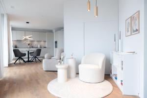 a white living room with a white chair and a table at Laya Living Lucerne - Kriens in Lucerne +12 photos