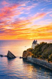 a house on a cliff near the ocean at sunset at SURF HOSTEL BIARRITZ in Biarritz
