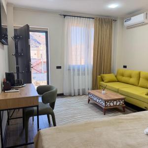 a hotel room with a yellow couch and a desk at AMare guesthouse in Kapan