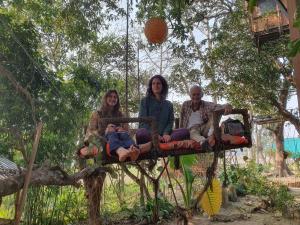 a group of three people sitting on a swing at Pemsee's Tree Town - Eco Treehouse Hostel in Sauraha