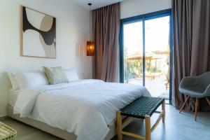 a bedroom with a bed and a chair and a window at Maison soli Marrakech in Bou Khaoua