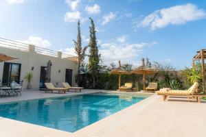 a swimming pool with chairs and umbrellas next to a house at Maison soli Marrakech in Bou Khaoua +31 photos