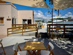 a patio with tables and chairs and an umbrella at Pousada Pássaros Park in Itapoa