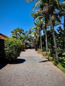 a gravel pathway with palm trees and a fence at Pousada Pássaros Park in Itapoa +102 photos