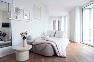 a white bedroom with a bed and a table at Laya Living Lucerne - Kriens in Lucerne