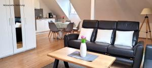a living room with a black leather couch and a table at Ferienhaus Südwind Rhauderfehn, in Rhauderfehn