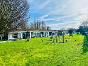 a park with benches and a playground in front of a building at Bungalow 44 - The Norfolk Broads At Your Door in Lowestoft