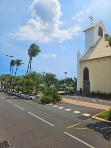 a church next to a street with palm trees at Le paille en queue in Saint-Pierre