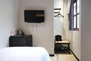 a bedroom with a bed and a tv on the wall at Asphodel Inn - Newly Renovated in Singapore