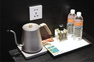 a tea kettle and two bottles of water on a table at Asphodel Inn - Newly Renovated in Singapore