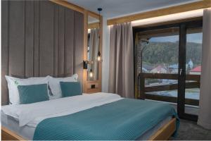 a bedroom with a large bed and a balcony at Forest Green & Spa in Gura Humorului +92 photos