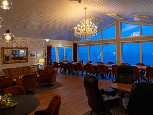 a restaurant with a long table and chairs and windows at Arctic Panorama Lodge in Uløybukta