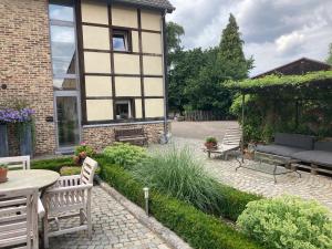 a patio with a table and chairs in front of a building at 'tMaelhof in Voeren