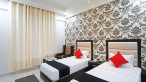 two beds in a hotel room with red pillows at Hotel Aroma Regency in Meerut