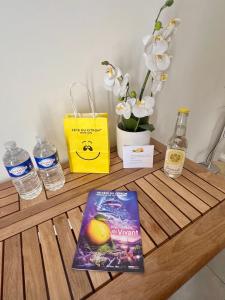 ein Tisch mit einem Buch, etwas Wasser und Blumen in der Unterkunft Studette de 17m2 avec parking privé gratuit Climatisation et petite cuisine in Menton