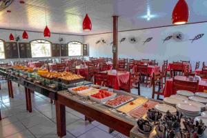 a buffet of food in a restaurant with red tables and chairs at Apartamento com sala e cozinha no morro da saudade in Morro de São Paulo