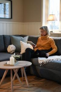 a woman sitting on a couch in a living room at GrebbestadFjorden stugor in Grebbestad