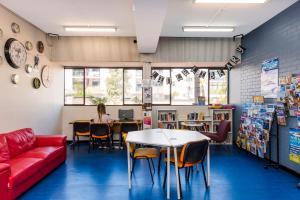a classroom with a red couch and a table and chairs at Billabong Backpackers Resort in Perth